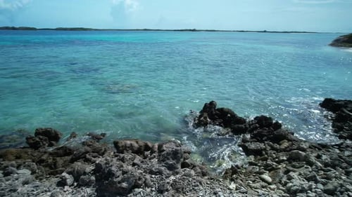 Crystal-clear turquoise waters meet rugged rocky shores under a bright sunny sky