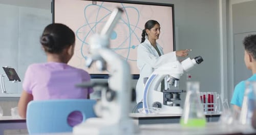 In school, teacher in lab coat engaging students in science classroom