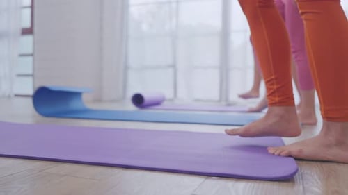 Close up of sportswoman preparing exercise mat in the fitness studio.