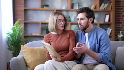 Shocked Couple Reads Bad News on Sofa