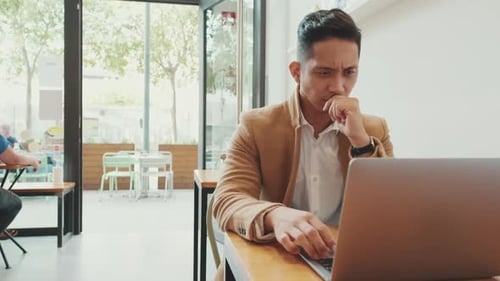 Junger Geschäftsmann, Freelancer, arbeitet mit Laptop am Tisch im Café
