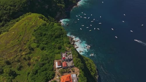 Aerial view of cliffside, ocean, and boats at Manta Point, Indonesia.