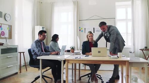 Diverse business team collaborates on laptop in modern office space