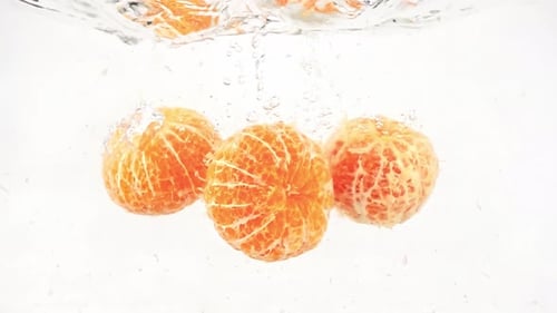 Peeled Tangerines Sinking Slowly in Clear Water Tank