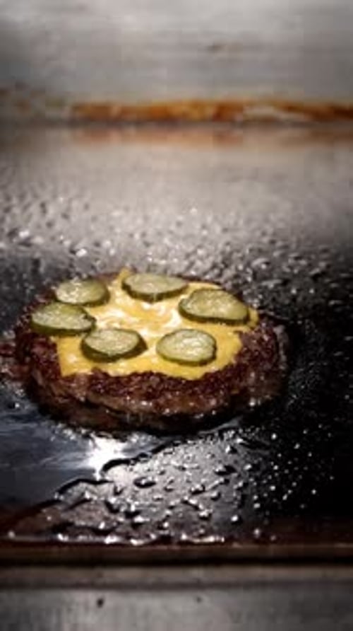 Melting Cheese Over a Juicy Burger Patty on the Grill