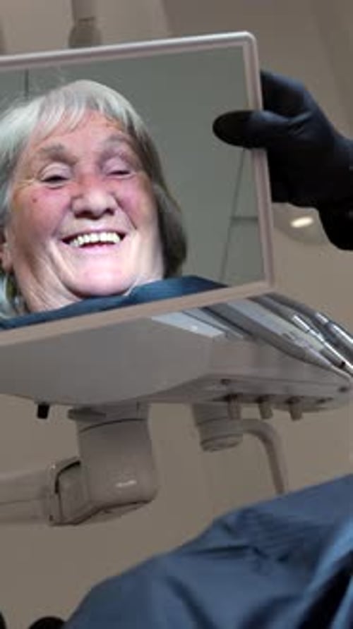 Senior Woman Smiles Looking at Dental Work in Mirror