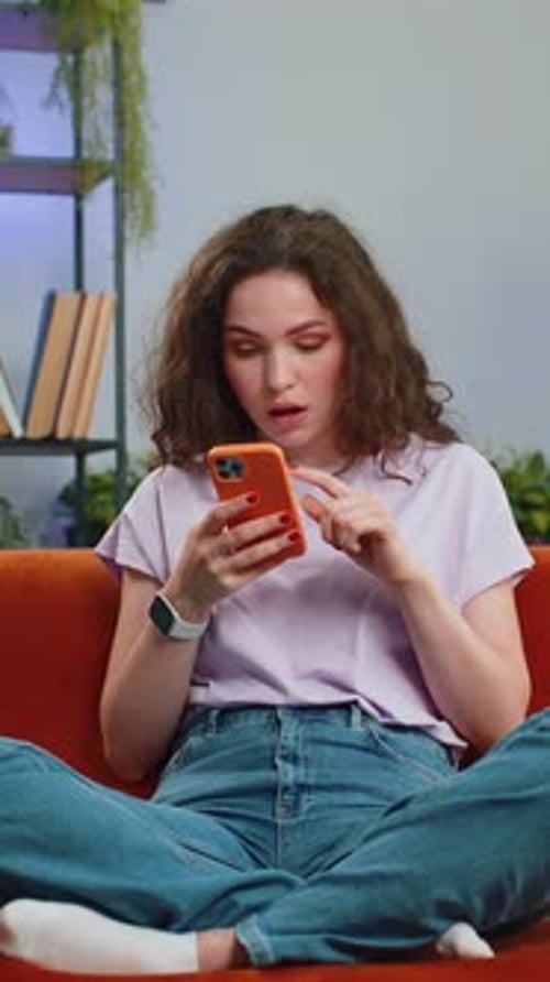 Frustrated Woman Throws Phone on Couch Indoors