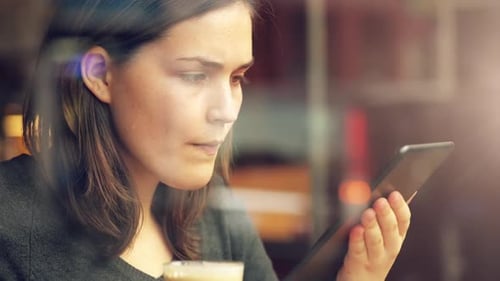 4k video footage of a young businesswoman using a digital tablet while at a coffee shop
