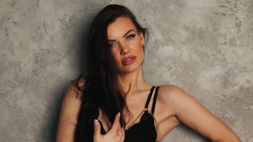 Elegant Woman Posing in Front of Gray Wall