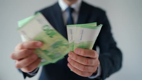 Primer plano de un hombre vestido formalmente contando billetes en euros