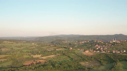 Filmmusik Drohnenflug über Berge mit grünem Wald und ländlichem Dorf inmitten von Bergen.
Sonnenuntergang