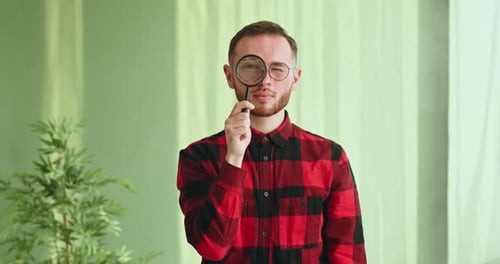 Man Holding Magnifying Glass to Eye Indoors