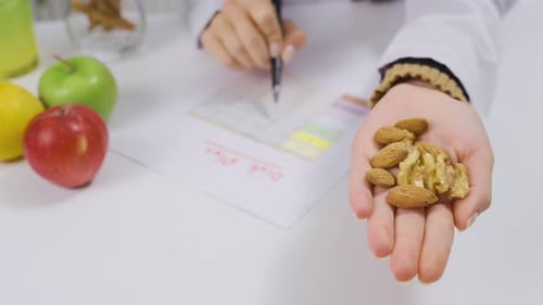 Nutritionist holding almonds and walnuts in healthy lifestyle concept.