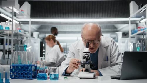 Scientist Looks Through Microscope at a Research Lab