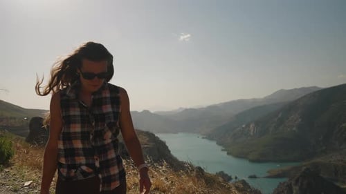 Pensive Woman with Flowing Hair Stands by the Mountain Edge, Plaid Shirt Adding Casual Style.