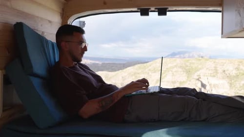 Digital Nomad trabalhando em um netbook a partir de um trailer com vista panorâmica da montanha