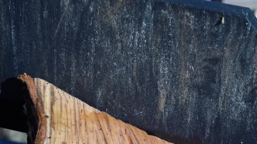 Wood splitter blade cuts through piece of birch firewood. Macro close up slow motion.
