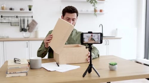 Man Opens Box and Reacts to Camera in Kitchen