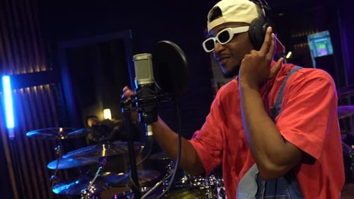 Young stylish singer recording music in professional studio