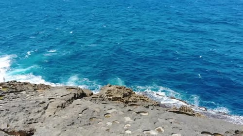 Aerial footage of a rock formation in a beach flying from left to right.