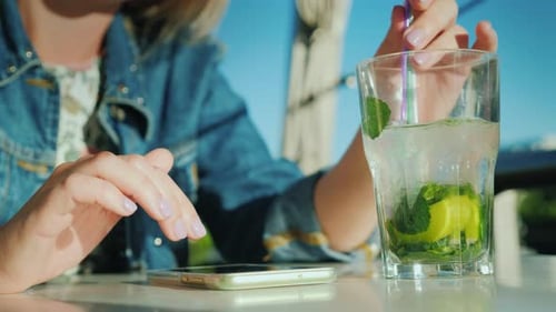 A Woman is Using a Smartphone in a Cafe