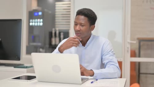 Young Adult Works at Laptop in Office