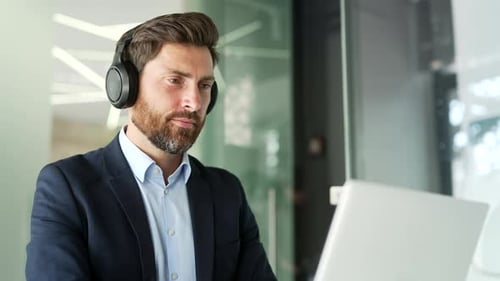 Man Working on Laptop with Headphones in Office