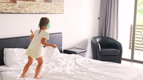Energetic Girl Dancing with Headphones on Bed