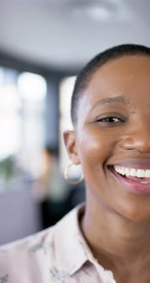 Vertical video of smiling african american businesswoman in office, slow motion, copy space