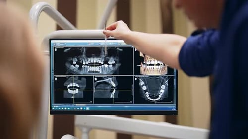 Dentist Talking Gesturing and Showing Results of Xray Teeth on Monitor Screen to Patient in Dental