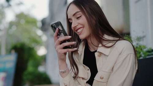 Smiling Young Adult Using Mobile Phone in City