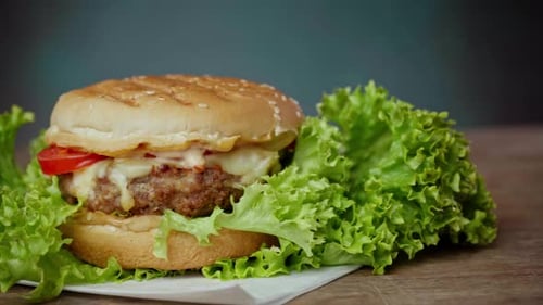 Close up of Big Burger lies on craft white paper against wooden table