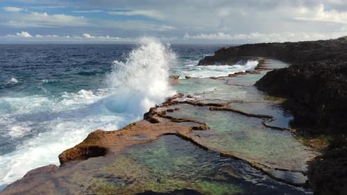 Pacific Ocean waves crash against rocks forming natural pools at Cap Des Pins. New Caledonia