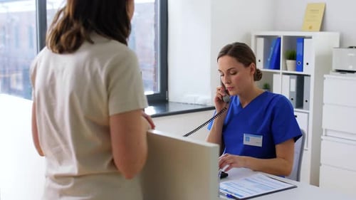 Woman in scrubs talks on phone in hospital reception