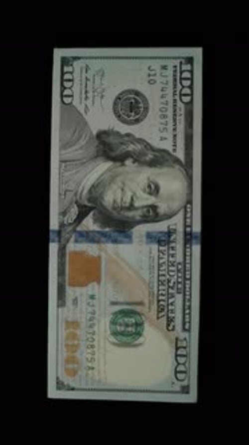 Vertical video. Concept Of Wasting Money. Hundred-Dollar Bills Fly Out Of A Stack One By One.