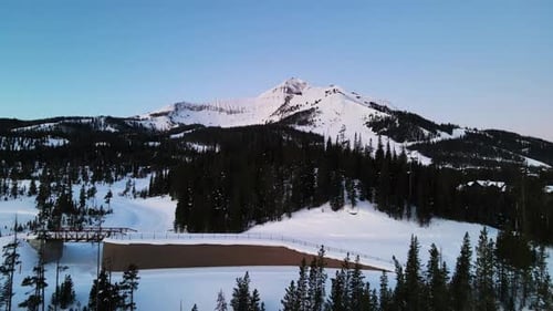 A drone shot of snowy Big Sky, Montana in winter, showcasing the ski resort and majestic mountain te