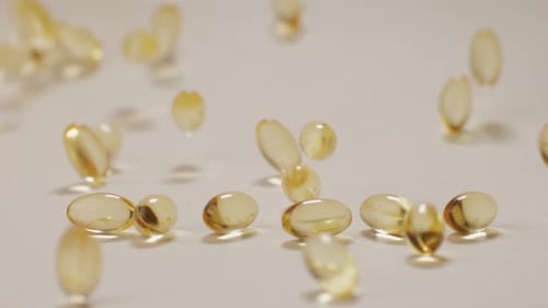 Omega Fish Oil Pills Dietary Supplement Falling Down on White Background Omega Fish Oil Softgels