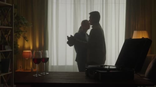 Vintage Record Player and Glasses with Red Wine on the Table Close Up A Couple is Dancing a Slow