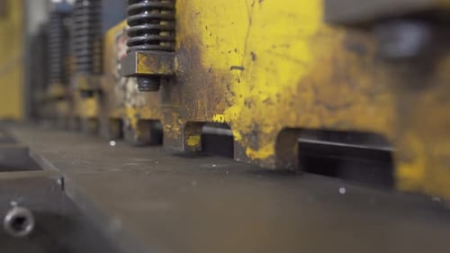 Close up shot of an automated metal shear, cutting steel, inside a industrial factory