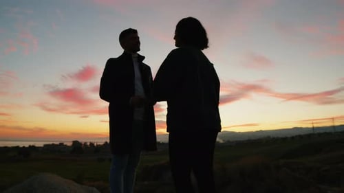 Silhouetted Couple Holding Hands at Sunset