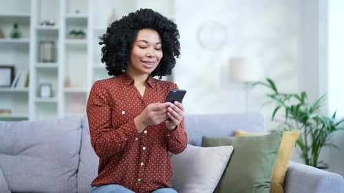 Woman Using Smartphone on Sofa at Home