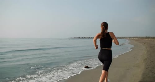 Young Woman Runs on Sandy Ocean Beach
