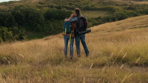 Rear view of couple with backpacks hiking together.