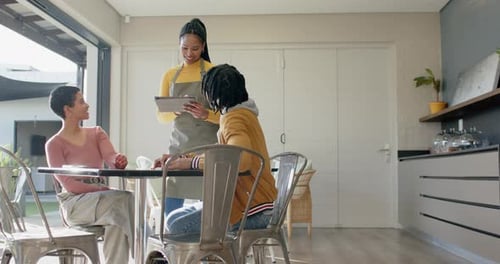 Female server responding to couple request and scrolling tablet menu at home dining table
