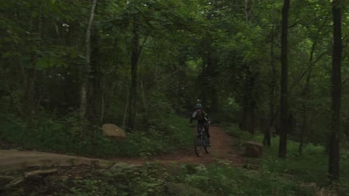 person wearing a helmet riding on a bicycle on a bicycle trail in the forest