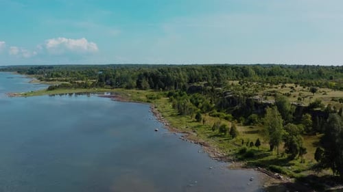 Aerial view of Baltic sea shore by verdant landscape. Rocky cliff side with trees and forest in a di