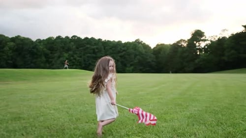 Child Running with American Flag in Grassy Field