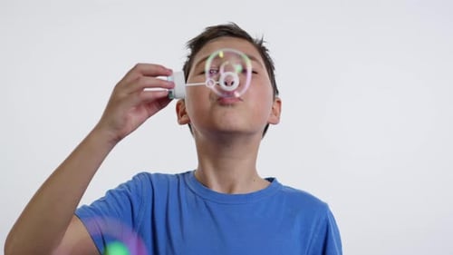 Boy Blowing Soap Bubbles on White Background