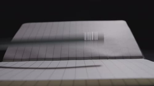 Close up of a pencil being laid down on an open notebook
