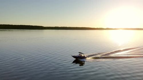 Cinematic Silhouette of Motorboat cruising on Calm Water Lake during golder hour sunset